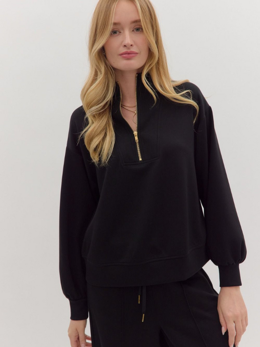 Woman wearing a black zip-up sweatshirt on a plain background