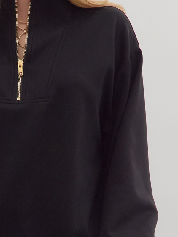 Black pullover with a gold zipper on a gray background