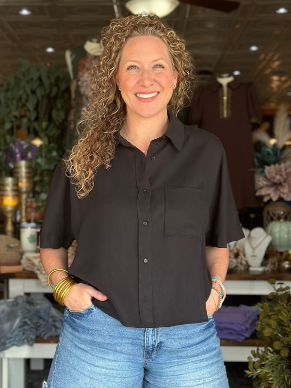 Woman wearing a black shirt and blue jeans standing in a room with decorative elements.