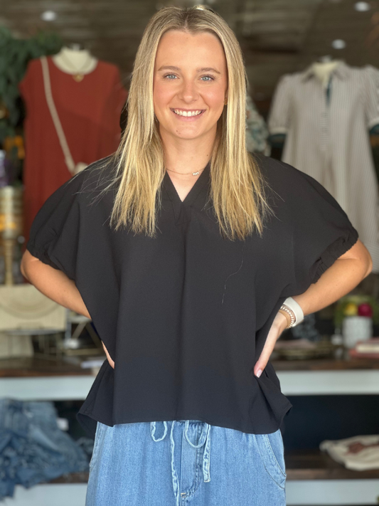 Woman wearing a black top and blue jeans in a clothing store.