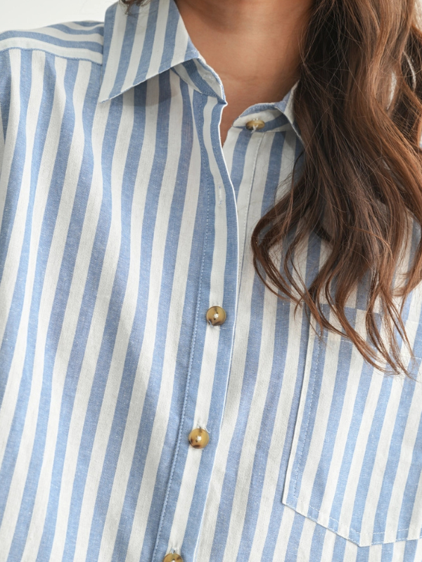 Close-up of a person wearing a blue and white striped shirt with a blurred background