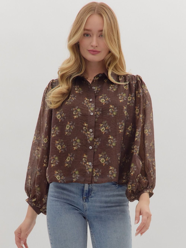 Woman wearing a brown floral blouse and blue jeans on a white background