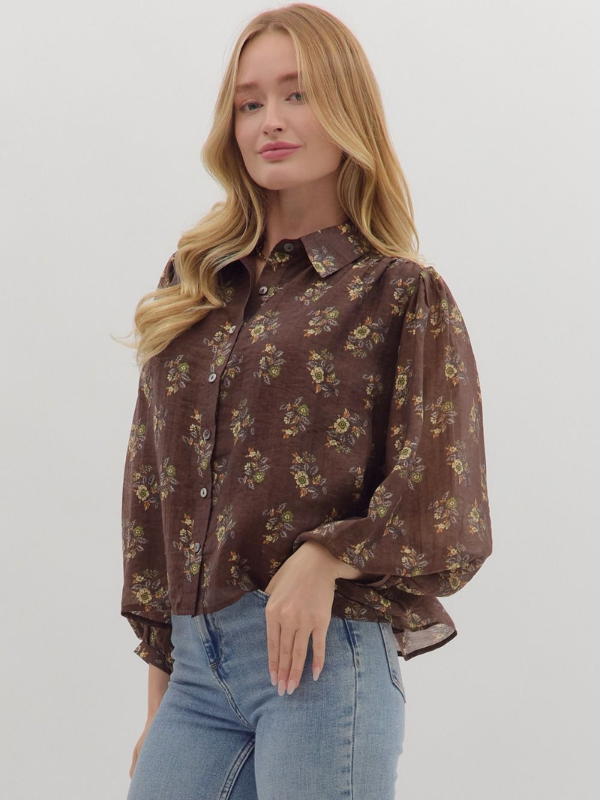 Woman wearing a brown floral blouse and blue jeans on a white background