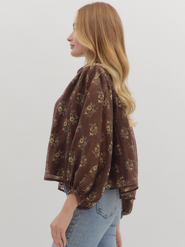 Woman wearing a brown floral blouse against a plain background