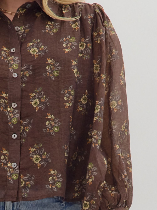 Brown floral patterned shirt on a hanger against a white background
