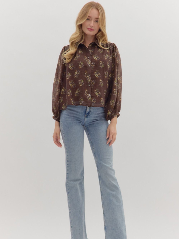 Woman wearing a brown floral blouse and light blue jeans on a white background