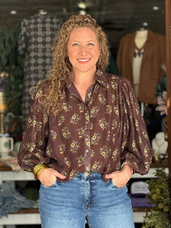 Woman wearing a floral blouse and jeans in a clothing store setting