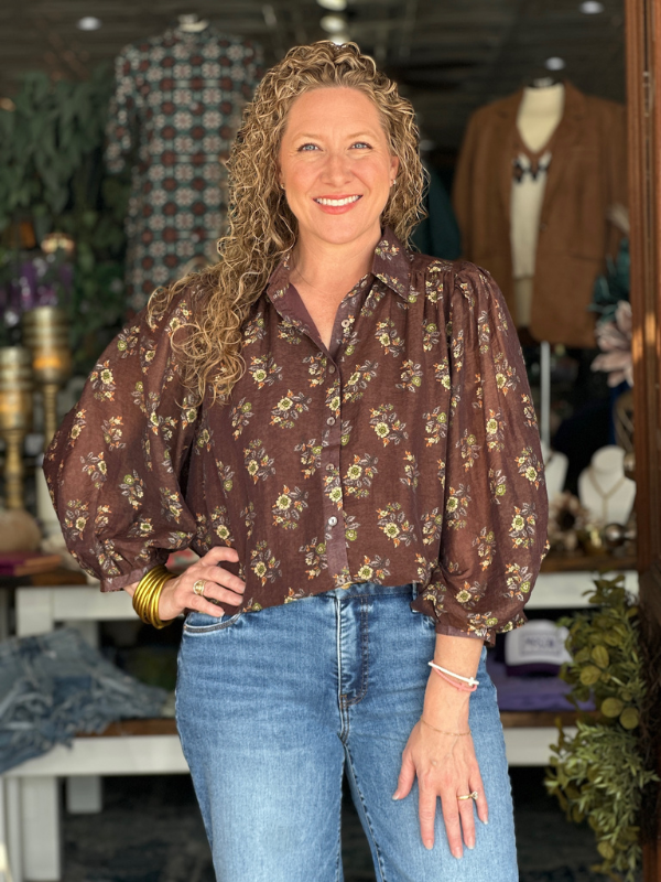 Woman wearing a floral blouse and jeans in a store setting