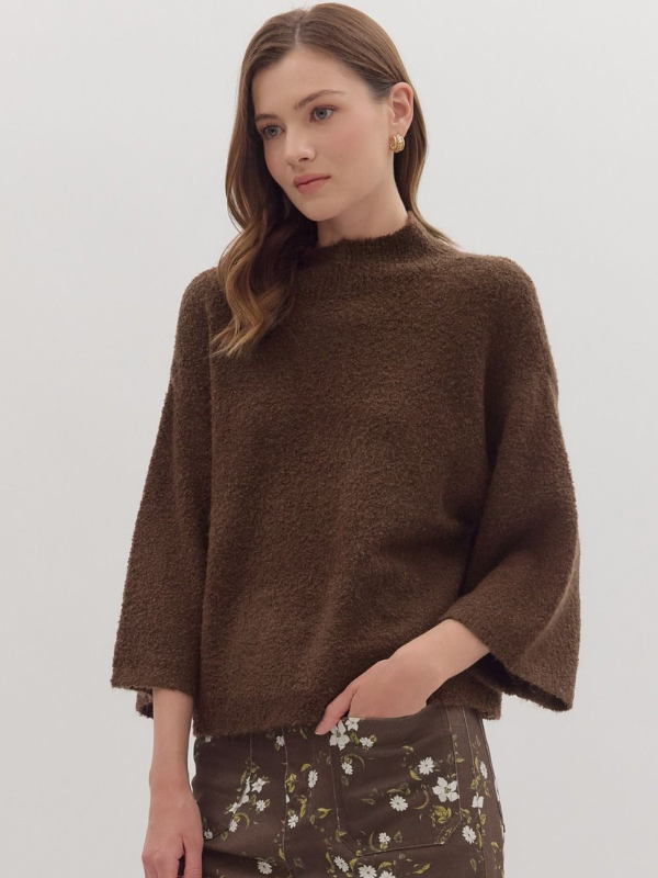 Woman wearing a brown sweater with a plain background