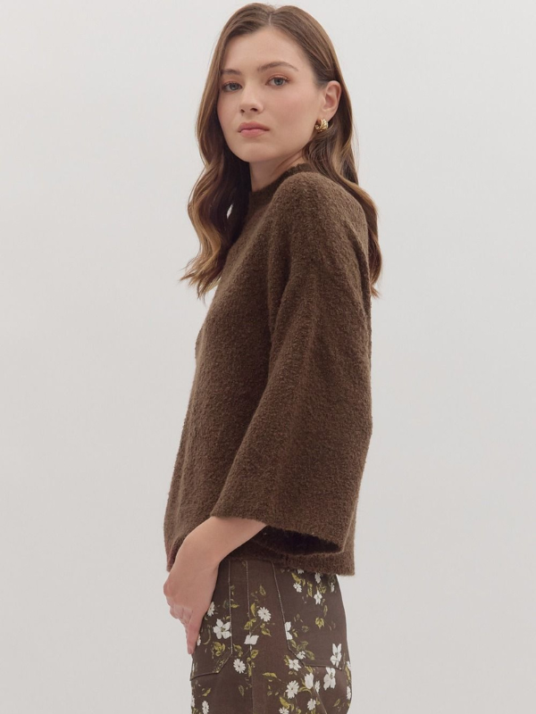 Woman wearing a brown sweater with a plain background