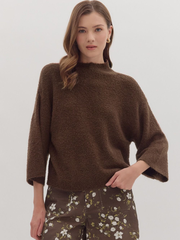 Woman wearing a brown sweater with floral pants on a white background