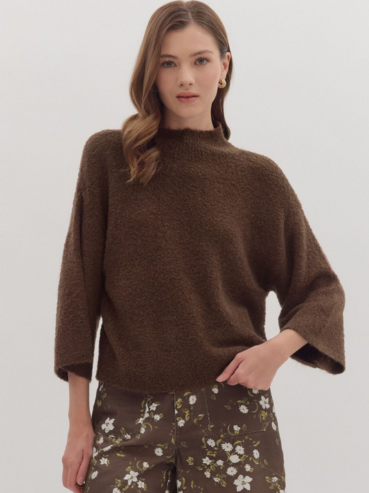 Woman wearing a brown sweater with floral pants on a white background