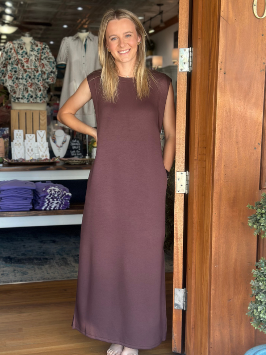 Woman in a long brown dress standing in a store doorway.