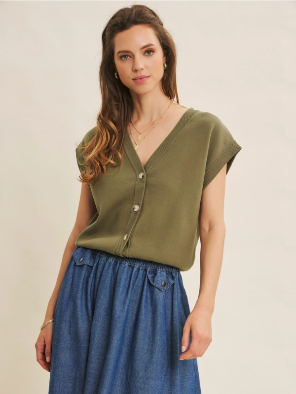 Woman wearing an olive green top and blue skirt on a beige background
