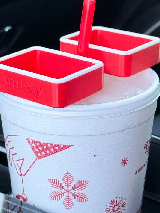 Two red and white cup holders with a straw in a white cup featuring red graphics.