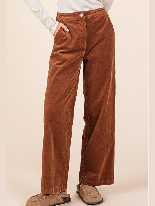 Brown corduroy pants worn by a person on a beige background