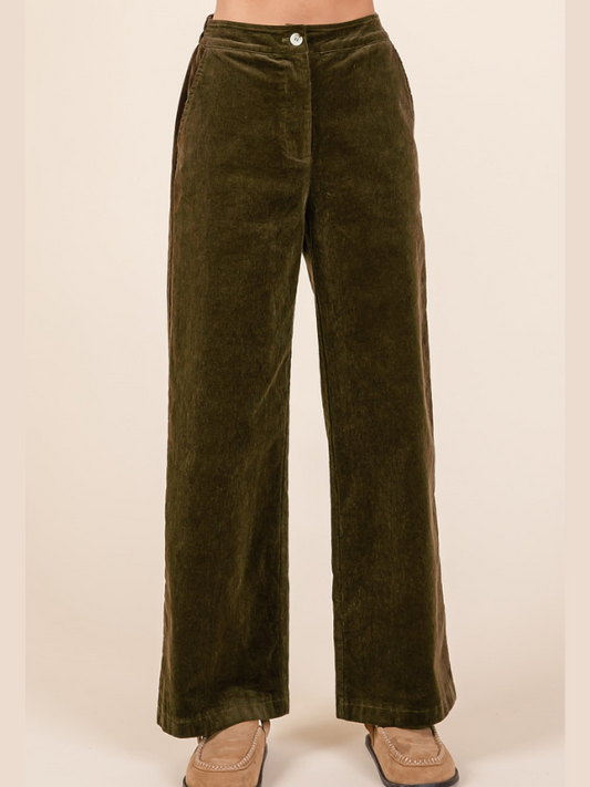 Green velvet pants on a beige background