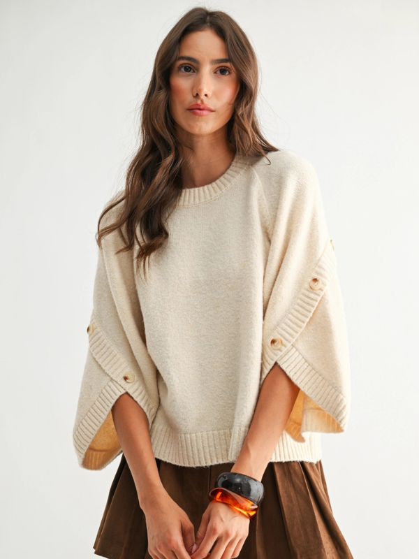 Woman wearing a beige poncho with a plain background