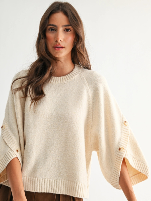 Woman wearing a beige poncho against a white background