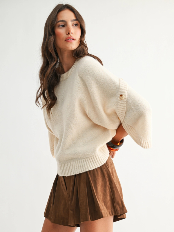 Woman wearing a cream sweater and brown skirt on a white background