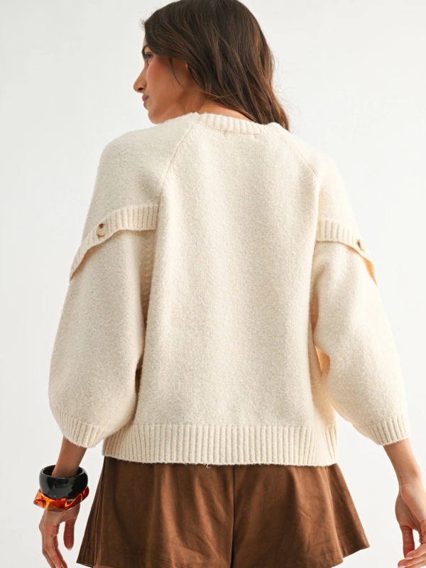 Woman wearing a cream sweater with a plain background