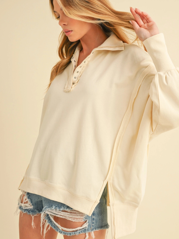 Woman wearing a cream-colored hoodie with denim shorts on a beige background