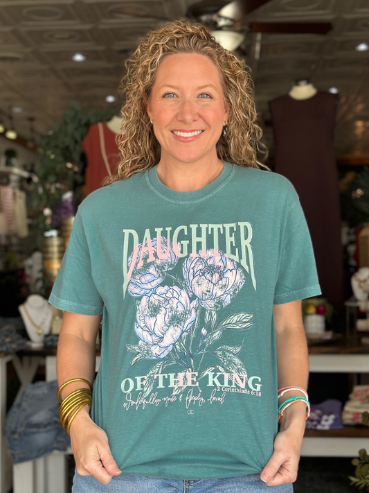 Woman wearing a teal t-shirt with floral design and text in a store setting