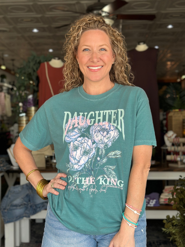 Woman wearing a teal t-shirt with floral design and text in a store setting
