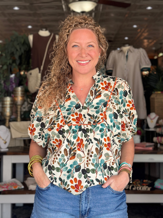 Woman wearing a colorful floral blouse in a store setting