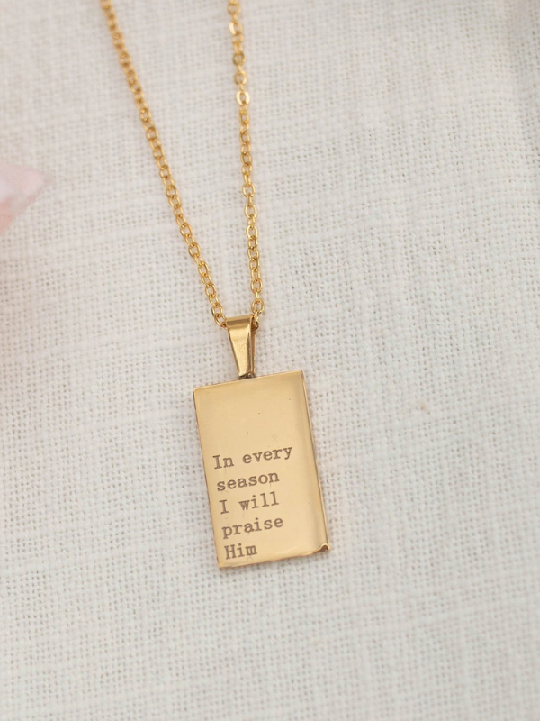 Gold necklace with a rectangular pendant on a light gray background