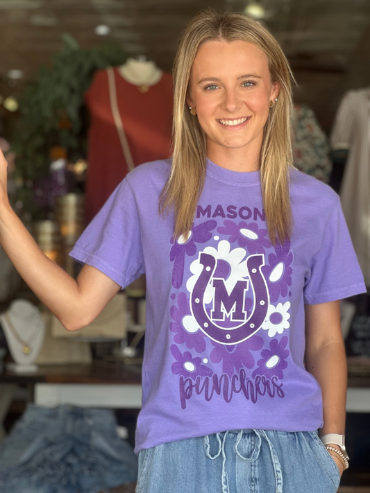Person wearing a purple t-shirt with a logo and text in a store setting