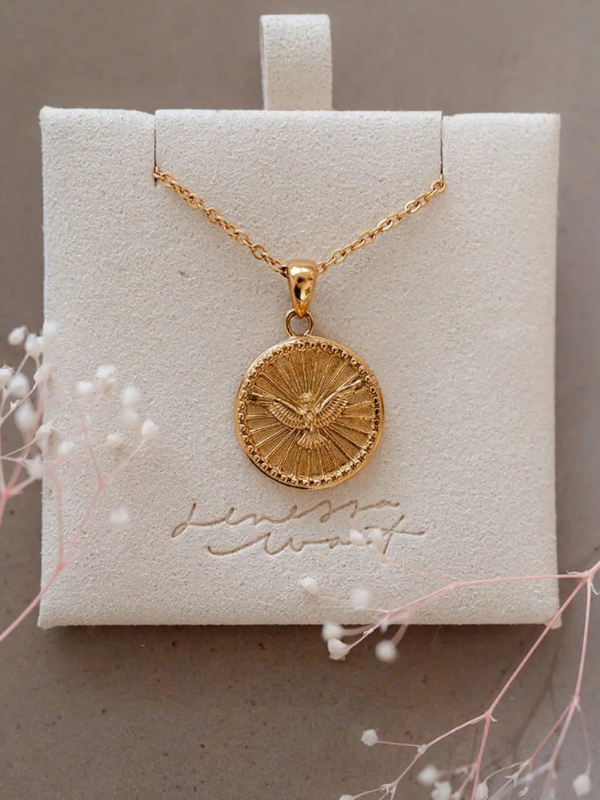 Gold necklace with a round pendant on a branded box