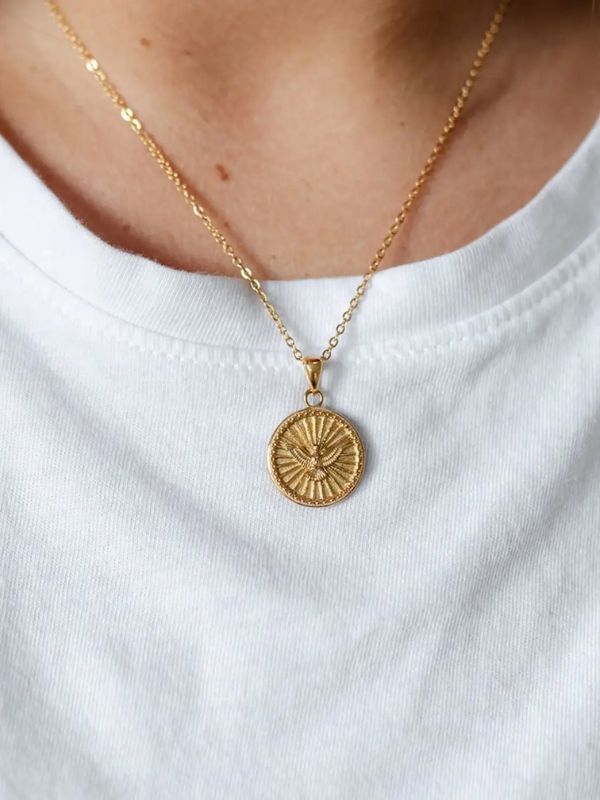 Gold necklace with a round pendant on a white shirt