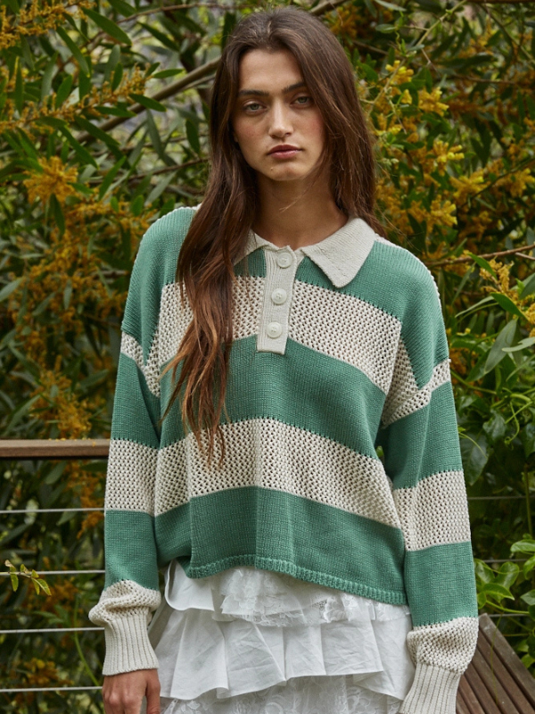 Woman wearing a green and white striped sweater with a collar, standing outdoors.
