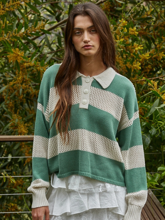Woman wearing a green and white striped sweater with a collar, standing outdoors.