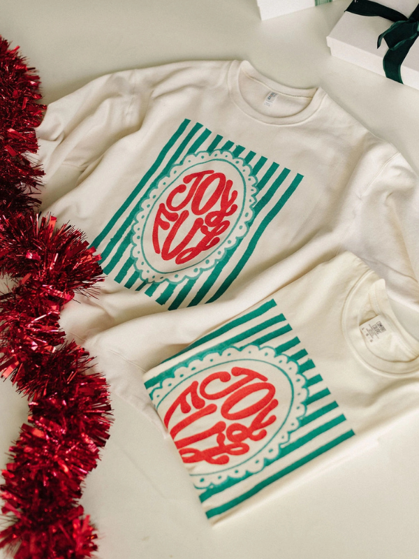 White sweatshirt with 'JOY' design on a light background