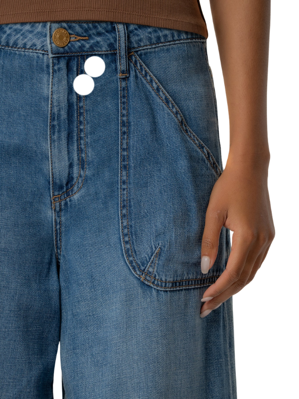 Close-up of a person wearing blue denim jeans with a brown ribbed top visible at the waistband, against a plain white background.