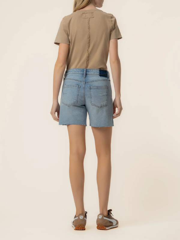 Person wearing a beige t-shirt and light blue denim shorts on a plain background