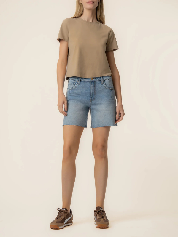 Person wearing a beige t-shirt and light blue denim shorts on a plain background
