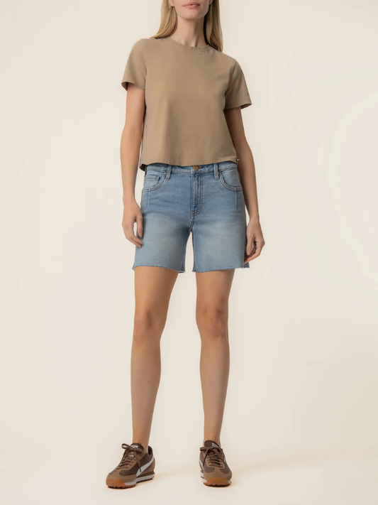 Person wearing a beige t-shirt and light blue denim shorts on a plain background