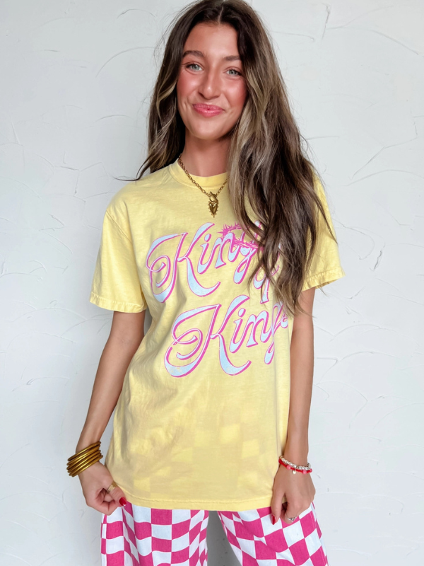 Person wearing a yellow t-shirt with pink text against a white background