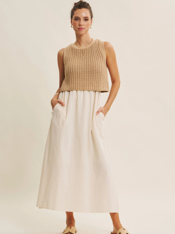 Woman wearing a beige sleeveless top and white skirt on a plain background