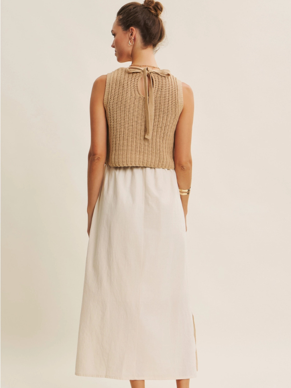 Woman wearing a beige sleeveless top and white skirt on a plain background