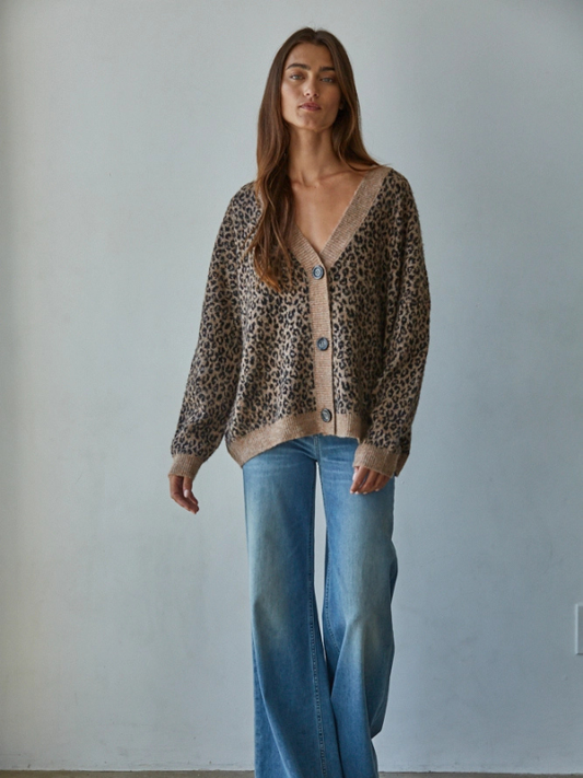 Woman wearing a leopard print cardigan and blue jeans against a plain background