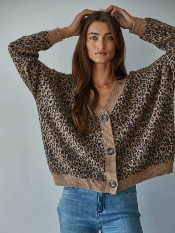 Woman wearing a leopard print cardigan with a plain background