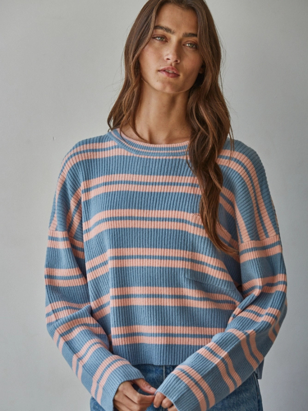 Woman wearing a blue and pink striped sweater against a gray background
