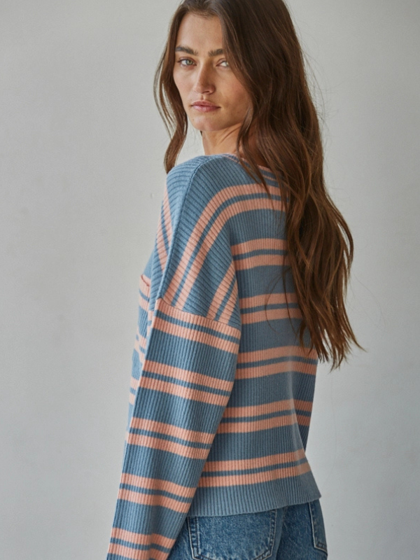 Woman wearing a blue and pink striped sweater against a plain background