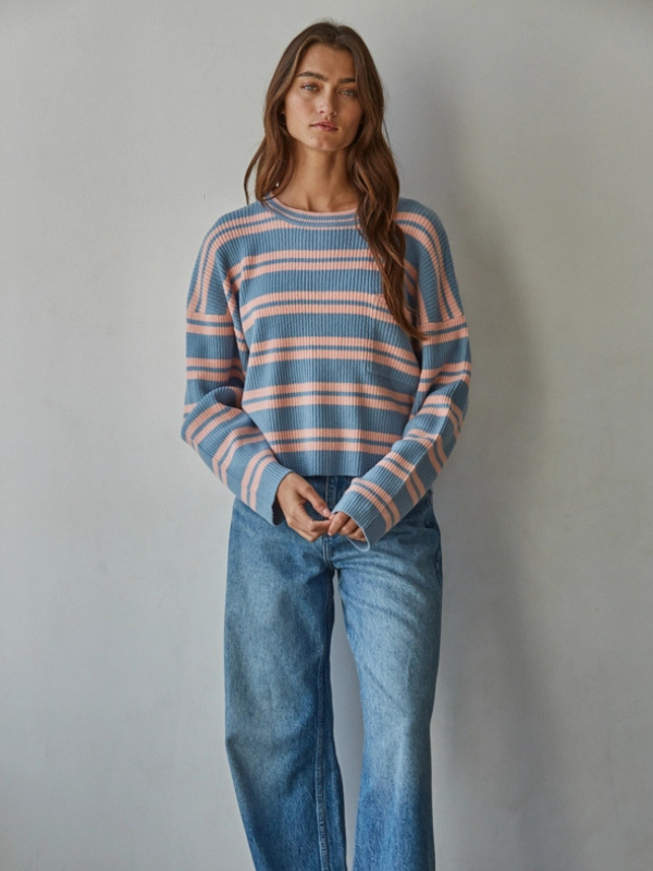 Woman wearing a striped sweater and jeans against a plain background