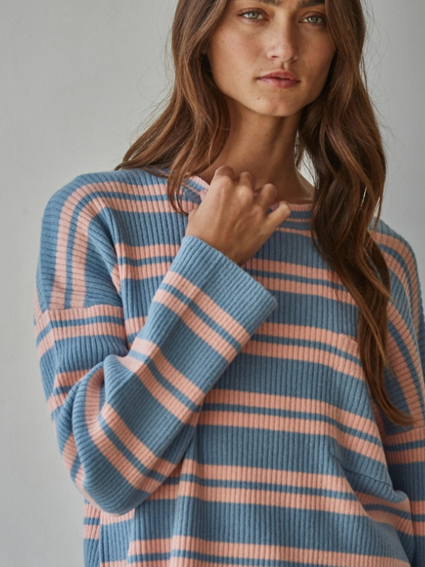 Woman wearing a blue and pink striped sweater against a neutral background