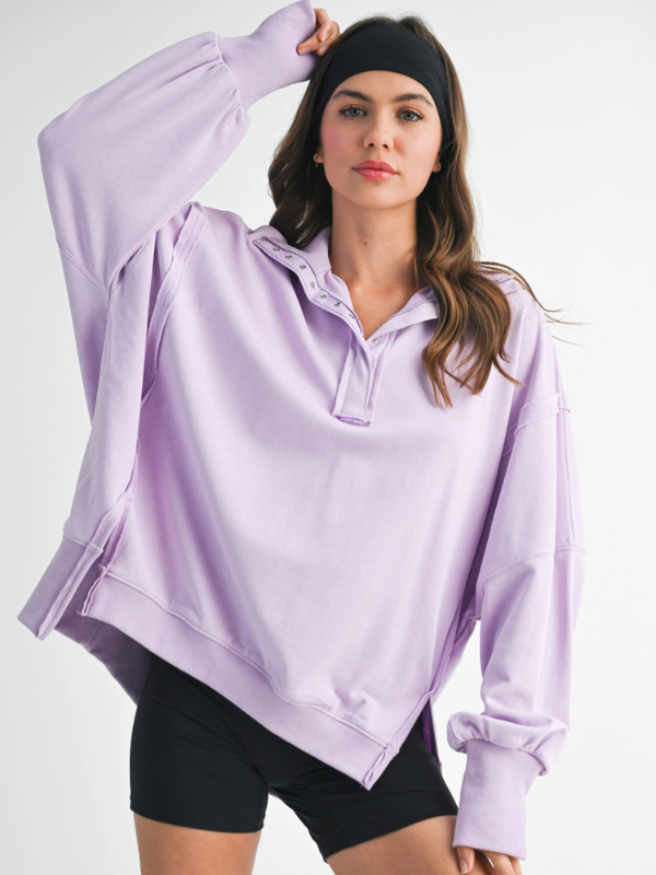Woman wearing a light purple long-sleeve shirt and black shorts on a white background
